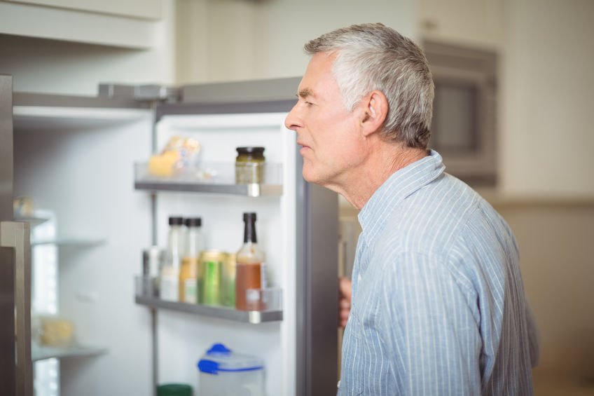 Mand åbner køleskabslåge mens han ser ind i køleskabet.